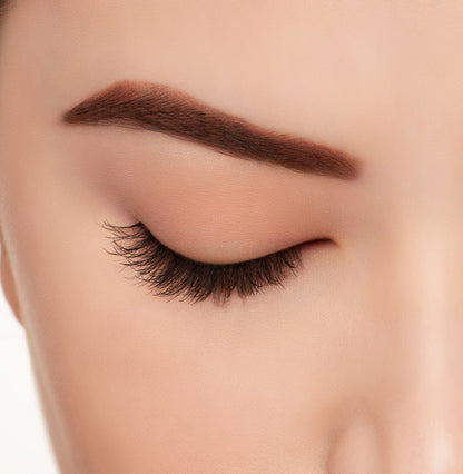 A model wearing Ardell's Ecolashes 453 on a closed right eye showing its extra-long layers with intense volume and fullness