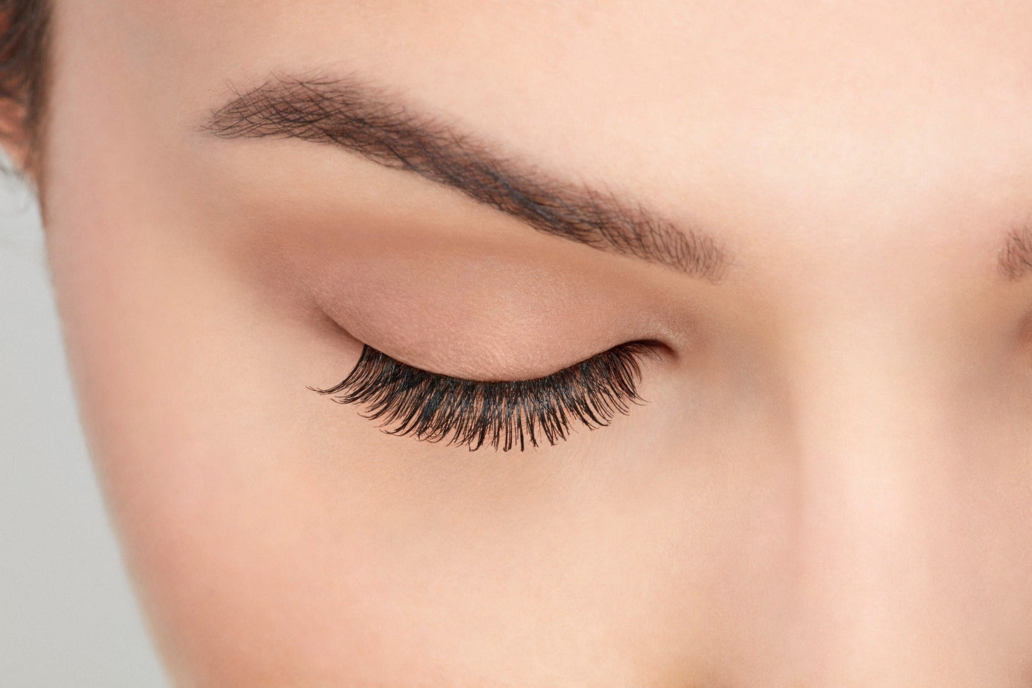 A model with a close right eye wearing Ardell Natural 110 showing how it looks undetectable & totally natural look