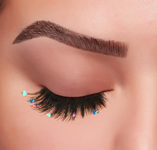 Closed eye with dramatic false lashes featuring colorful gem accents for a bold statement style.